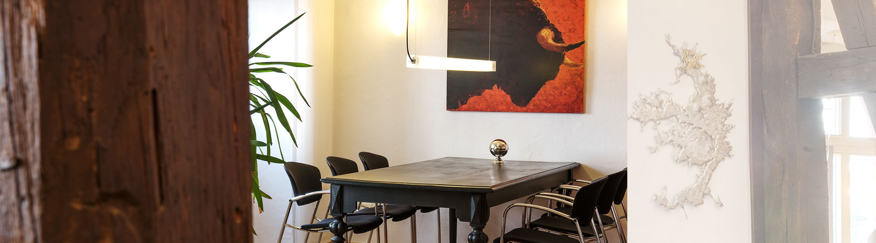 Besprechungsbereich im Büro von GLASSL IMMOBILIEN in Michelstadt mit historischen Holzbalken und modernem Tisch